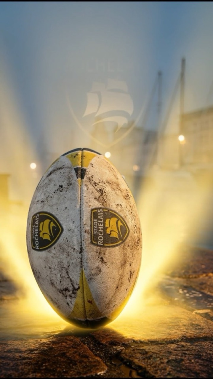 Un ballon de rugby posé sur les quais du port, entouré de lumière.
